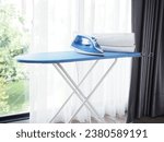 Electric steam iron and pile of clothes on ironing board