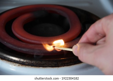 Electric Stove With A Spiral. Image Of An Electric Stove Heating Element. Red Hot, Glowing Element. The Hand Brings The Match To The Knee Coil, And The Sulfur Ignites. Burning Match And Electric Stove