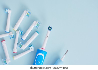 electric toothbrush and a lot of different multi-colored replaceable nozzles on blue background top view copy space - Shutterstock ID 2129944808