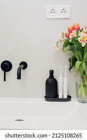 Electric Toothbrushes On A Black Stand With A Black Soap Dispenser In The Bathroom