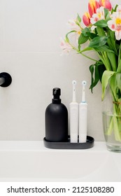 Electric Toothbrushes On A Black Stand With A Black Soap Dispenser In The Bathroom