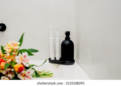 Electric Toothbrushes On A Black Stand With A Black Soap Dispenser In The Bathroom