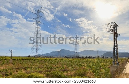 Electric tower. High voltage electricity pylons and transmission power lines in farm field. Electric tower in field. Power line towers in farmland. Electricity pylons and High voltage at mountains.