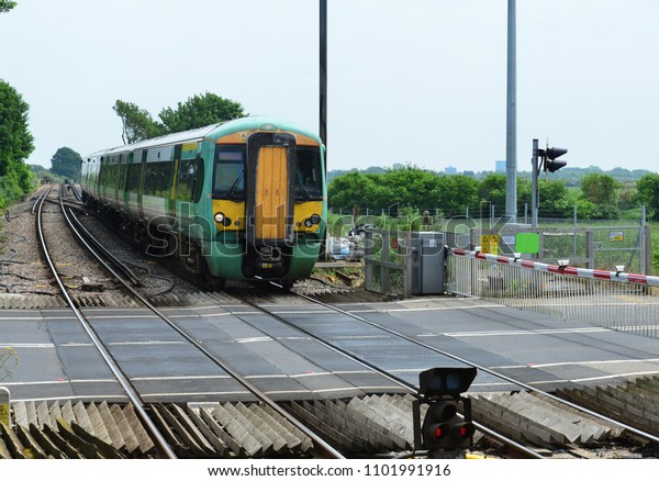 An\
electric train crossing a rail crossing in West\
Sussex