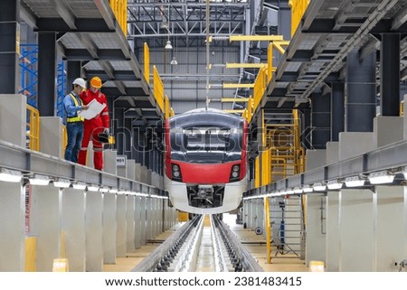 Electric train technician engineer with blueprints  checking controls system for security functions in maintenance infrastructure plant of sky train, public transportation vehicle,Teamwork management
