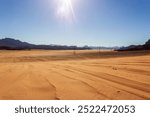 Electric transmission towers stretch across the Jordanian desert landscape, connecting distant regions through the arid, expansive terrain, with rugged mountains in the background