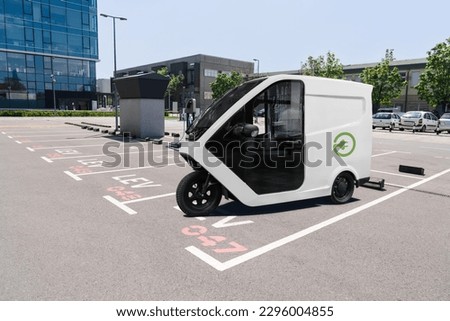 Electric tricycle scooter with charging station on a parking lot for LEV - light electric vehicles