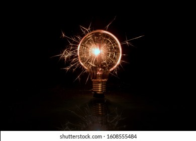 Electric Tungsten Lightbulb On A Black Background Emitting Sparks