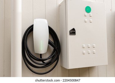 An Electric Vehicle Car Charger On The Wall Of A House With The Switch Break Box Next To It