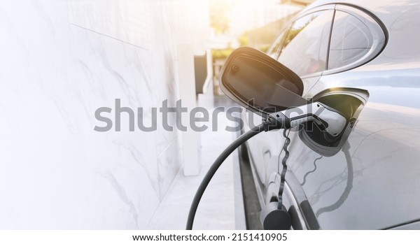 Electric vehicle is charging with cable power at\
charging station.