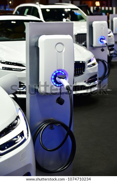 Electric Vehicle charging in\
station with power supply plugged into an electric car being\
charged.