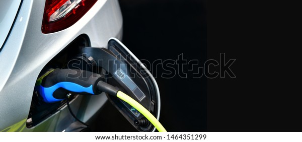 Electric Vehicle\
charging in station with power supply plugged into an electric car\
being charged.Text\
space