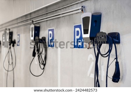 Electric Vehicle Charging Station in Private Garage Parking lot of Multifamily Building with Numbers and Control Panels. Underground Parking with Charge Points for Electro Car.