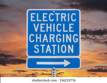 Electric Vehicle Charging Station Sign Isolated With Sunset Sky.