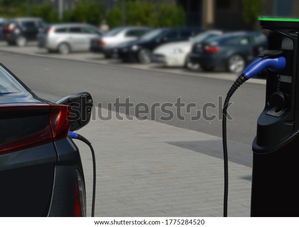 Electric vehicle or hybrid plug-in car\
connected to a charging station outdoors\
