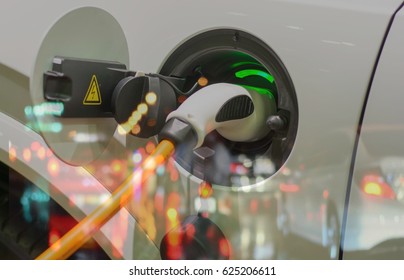 Electric vehicle , Smart car , Air pollution and reduce greenhouse gas emissions concept. Double exposure of charging Electric car with power cable supply plugged in and city night light view.