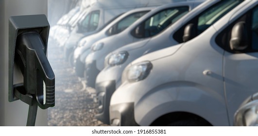 Electric Vehicles Charging Station On A Background Of A Row Of Vans. Concept