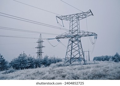Electric voltage tower, power line, electricity pylon at winter snow background.