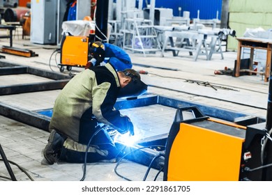 An electric welder works at an industrial enterprise. The process of welding a metal structure from a metal profile. Unrecognizable person. Foreground - Powered by Shutterstock