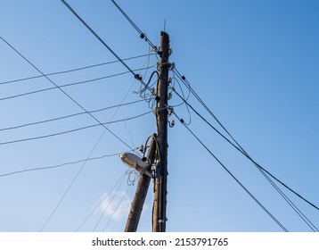 electric wires and a street lamp on an old wooden pole support against a background of blue sky with clouds. copy space.