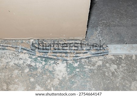 Electrical cables in corrugated conduits installing on concrete floor in an unfinished room