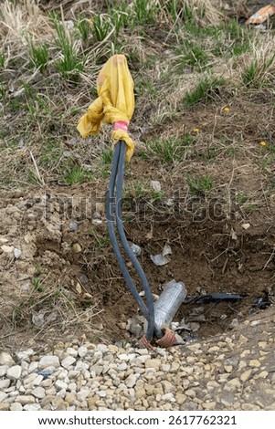 Electrical cables emerging from the ground covered with plastic bag