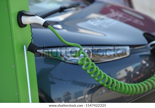 Electrical car plugged through a charging cable\
to a charging\
station.