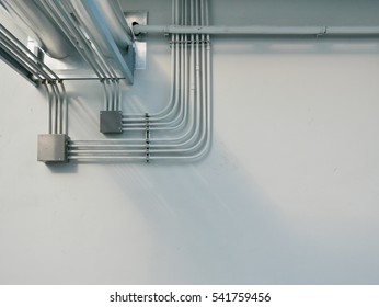 Electrical conduit and water tube duct on white wall background.