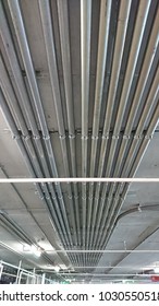 Electrical conduits, pipes of power lines and signal cables on congrete ceiling in building parking car