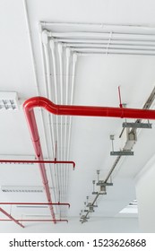 Electrical Conduits System White And Sprinkler System Fire Red Piping Installed On The Ceiling Of The Building.