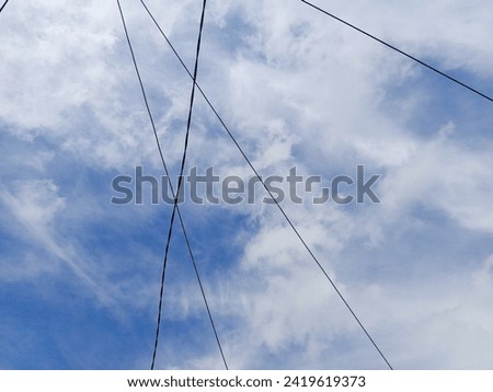 The electrical connecting cables crisscrossing above look beautiful against the backdrop of the bright blue sky.