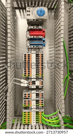 Electrical control panel with terminal blocks, DIN rail components and organized wiring inside industrial cabinet, automation and power distribution system, close up technical interior.