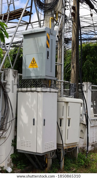 Electrical control\
socket and NODE cabinet on poles. Fiber optic junction box of high\
speed internet on the side with cement fence reinforced with steel\
frame. Selective\
focus