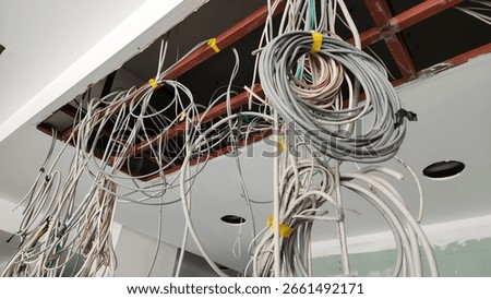 Electrical and Data cables hanging from the workplace ceiling made decorative arrangements