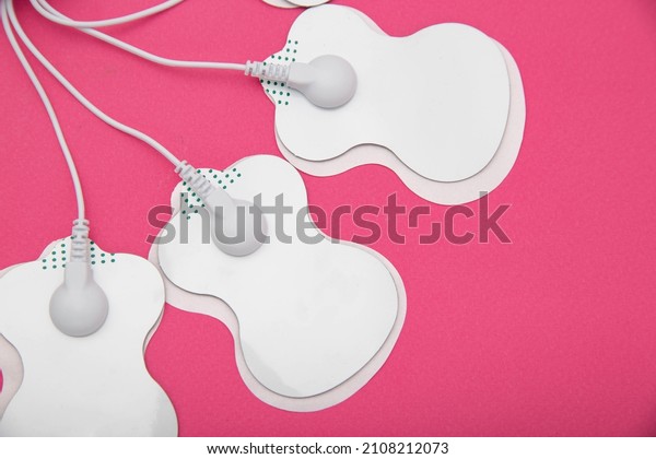 Electrical electrodes for stimulating the\
patient\'s body on a pink\
background.