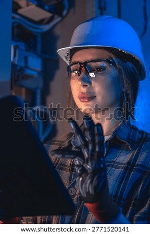Electrical engineer analyzing power system using tablet device. Technical equipment inspection.