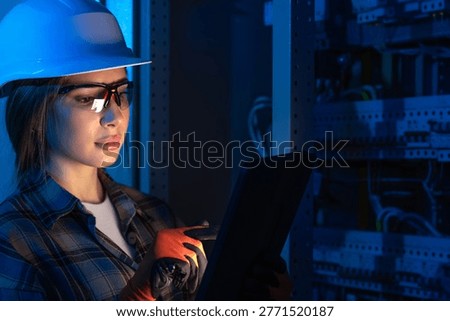 Electrical engineer analyzing power system using tablet near switchboard. Technical inspection.