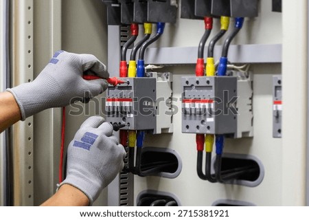 Electrical engineer checking the operation of electrical control cabinet, maintenance concept.	