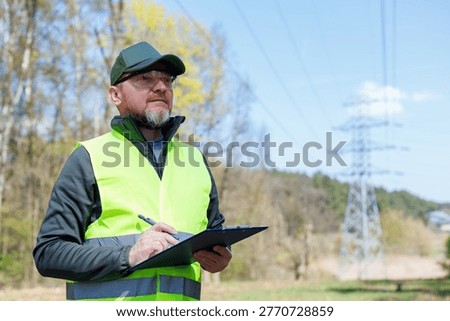 Electrical engineer or energy auditor inspecting power lines in the forest. Power grid maintenance and inspection. Ecologist assessing infrastructure impact on nature.