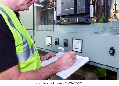 Electrical Engineer In Hi Viz Vest Making Notes And Inspecting Some Circuit Brteakers