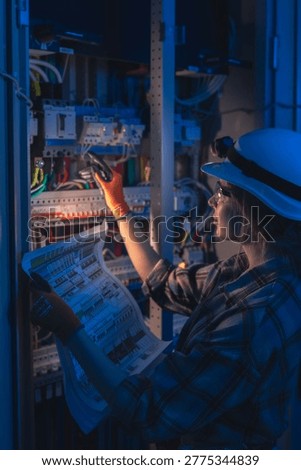 Electrical engineer inspecting power system blueprint near switchboard. Professional inspection.