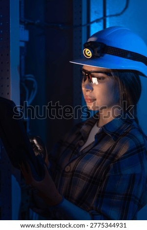 Electrical engineer inspecting power system with tablet near switchboard. Technical control.