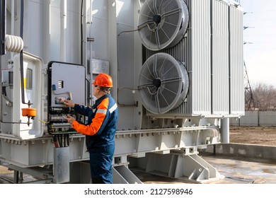 Electrical engineer inspecting electrical systems in equipment control cabinet using data from tablet
