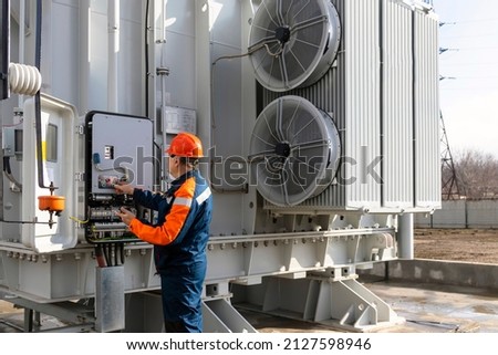 Electrical engineer inspecting electrical systems in equipment control cabinet using data from tablet