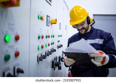 Electrical Engineer Reading Electric Scheme And Installations In Factory.