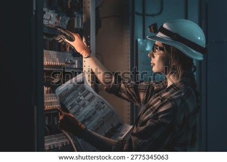 Electrical engineer reviewing power system blueprint near switchboard. Technical analysis.
