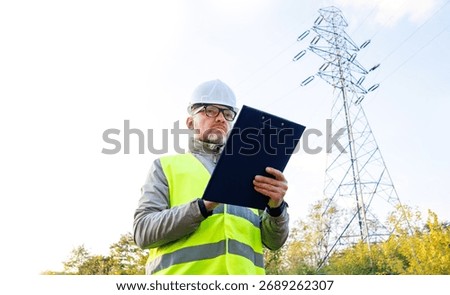 Electrical engineer stands next to power lines. Control electric management.