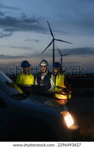Electrical Engineer and technical specialists working on electricity wind power station project , planing green energy facility at night