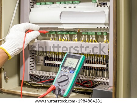 Electrical engineer tests the operation of the electric control cabinet on a regular basis for maintenance.