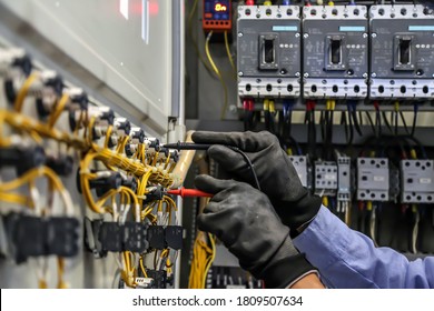 Electrical engineer using digital multi-meter is measuring equipment to checking electric current voltage at circuit breaker and cable wiring system in main power distribution board.